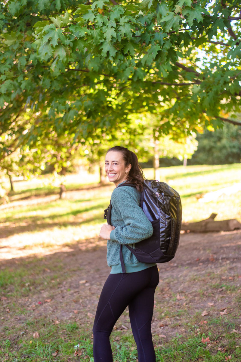 woman walking in the park with a black backpack