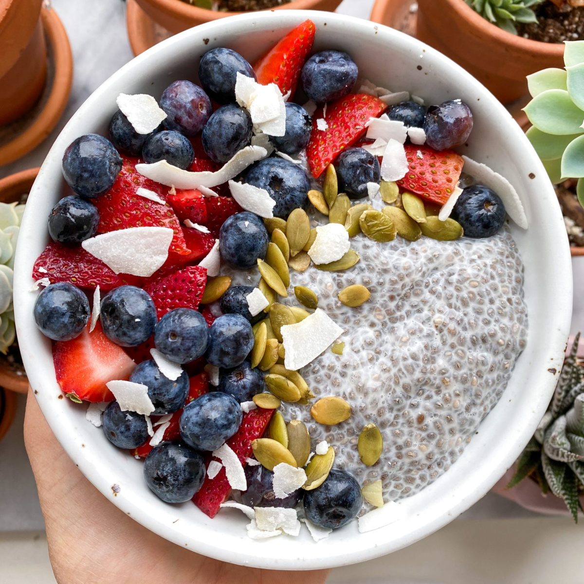 Bowl of chia pudding topped with fruit, nuts and granola