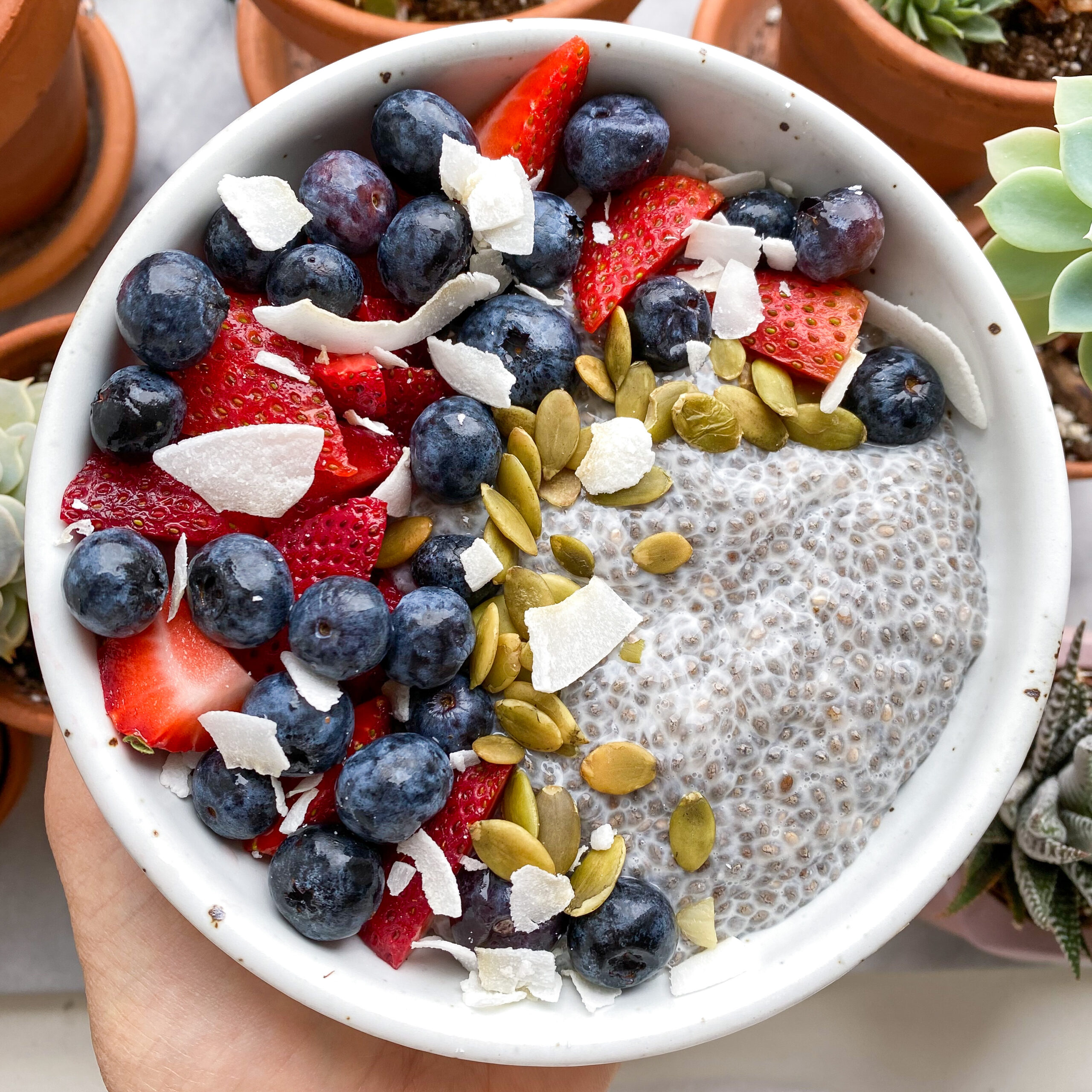 Bowl of chia pudding topped with fruit, nuts and granola